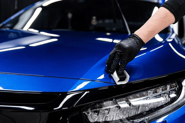 Detailer applying ceramic coating to blue car hood during professional detailing in Montreal-Laval