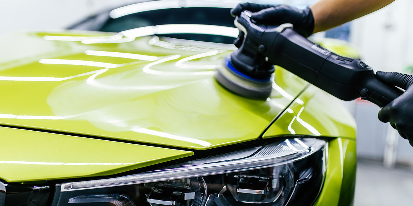 Professional detailer applying Elite+ Ceramic 3-Year coating on a yellow car for gloss and protection